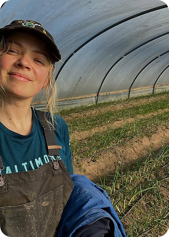 A woman smiling in a greenhouse on a farm.